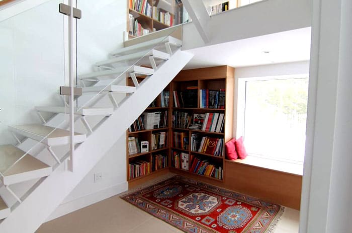 Der Platz unter der Treppe und um ihn herum fordert buchstäblich dazu auf, auf sich aufmerksam zu machen: Dies ist ein schicker Ort, um eine beliebige Anzahl von Büchern zu platzieren, ohne sich darüber Gedanken zu machen, wie der Schrank in den Stil des Raumes passt